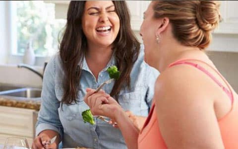 Two Women Laughing Together In Kitchen