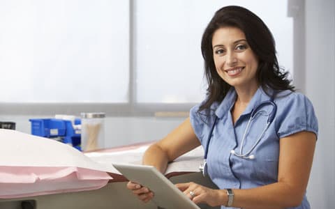 Gp Leant On Bed With Clip Board Smiling