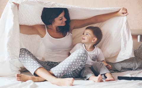 Mother And Child Playing Under Duvet