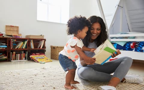 Mother Reading A Book To Young Child In Nursery