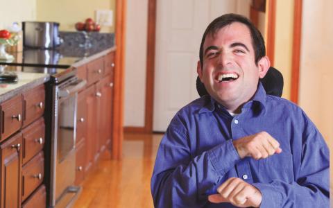 Man Smiling In Kitchen Sat In Wheelchair