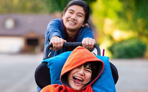 Young Girl Pushing Less Abled Brother In Wheelchair